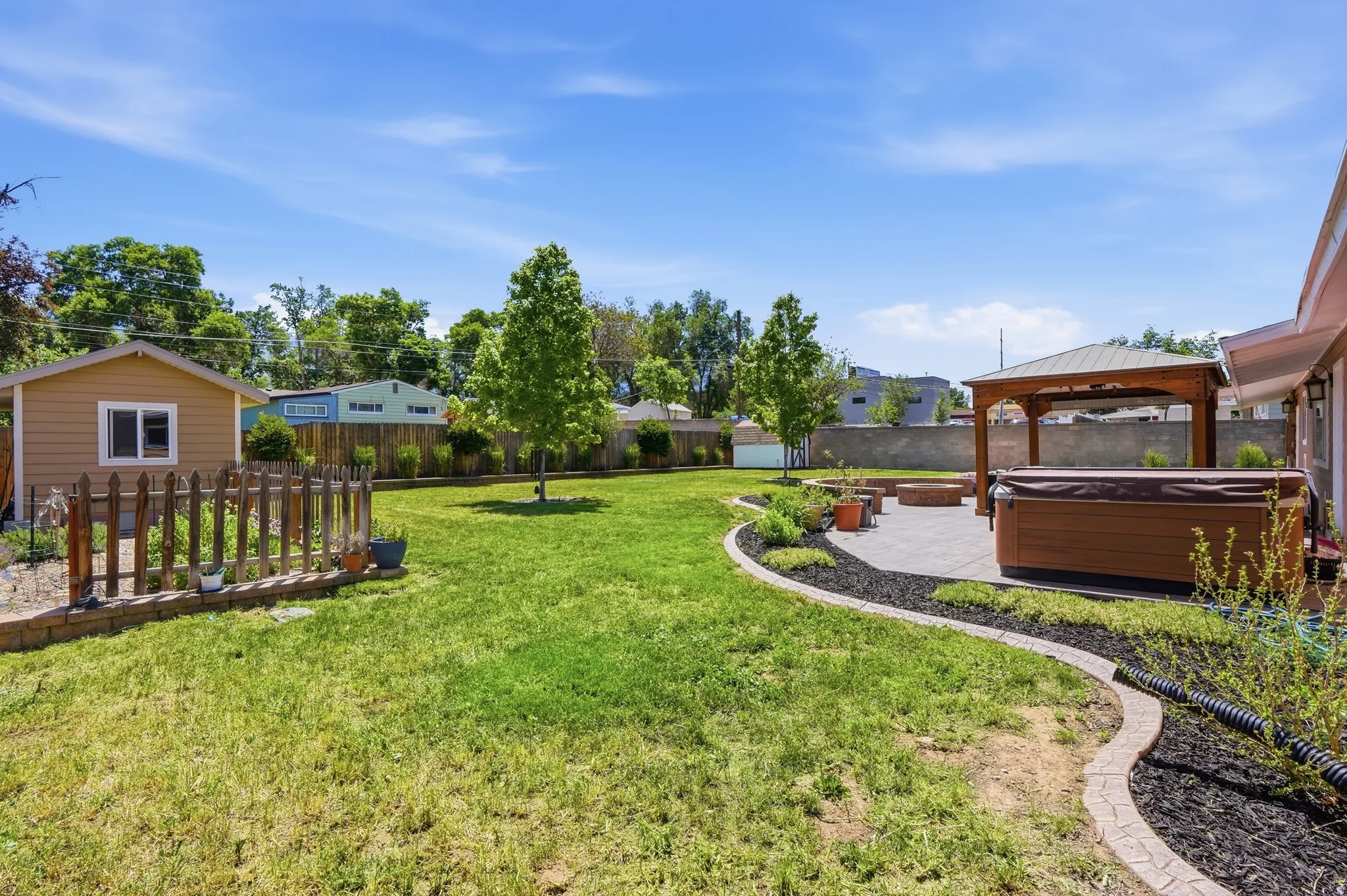 Expansive lawn with a paver patio featuring a hot tub and a wooden gazebo