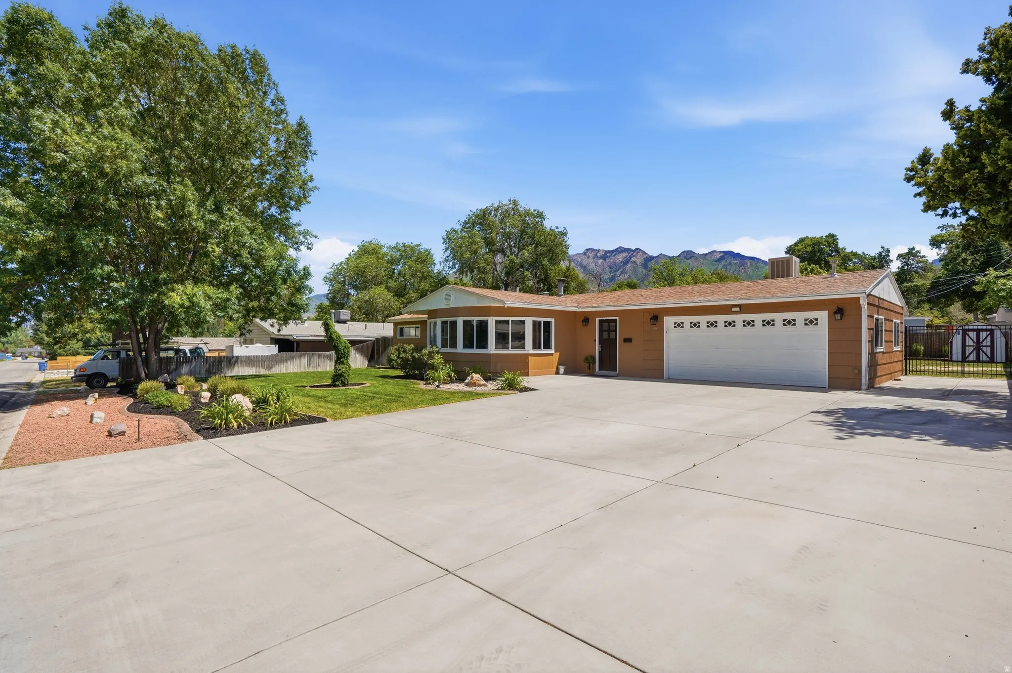 Single-story residence featuring a two-car garage with a white sectional door, a concrete driveway, and established front landscaping