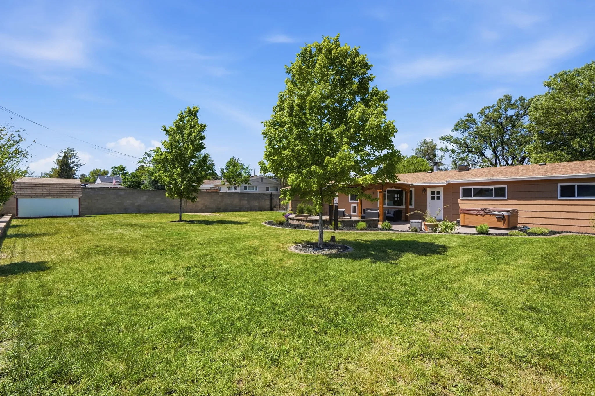 Expansive green lawn with mature trees and perimeter block wall