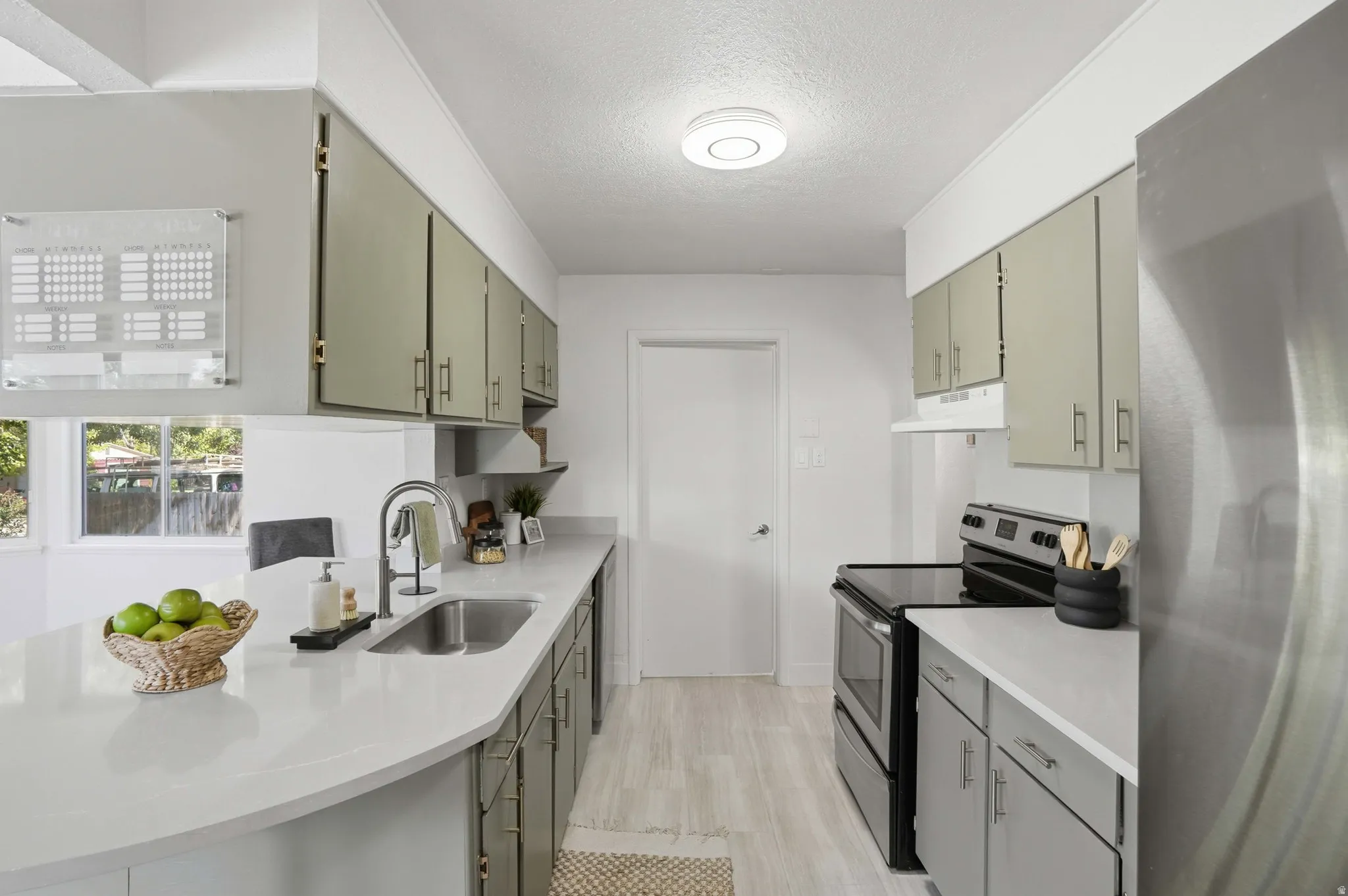 Open-concept kitchen featuring light-toned cabinetry, a stainless steel sink with a gooseneck faucet, quartz countertops.