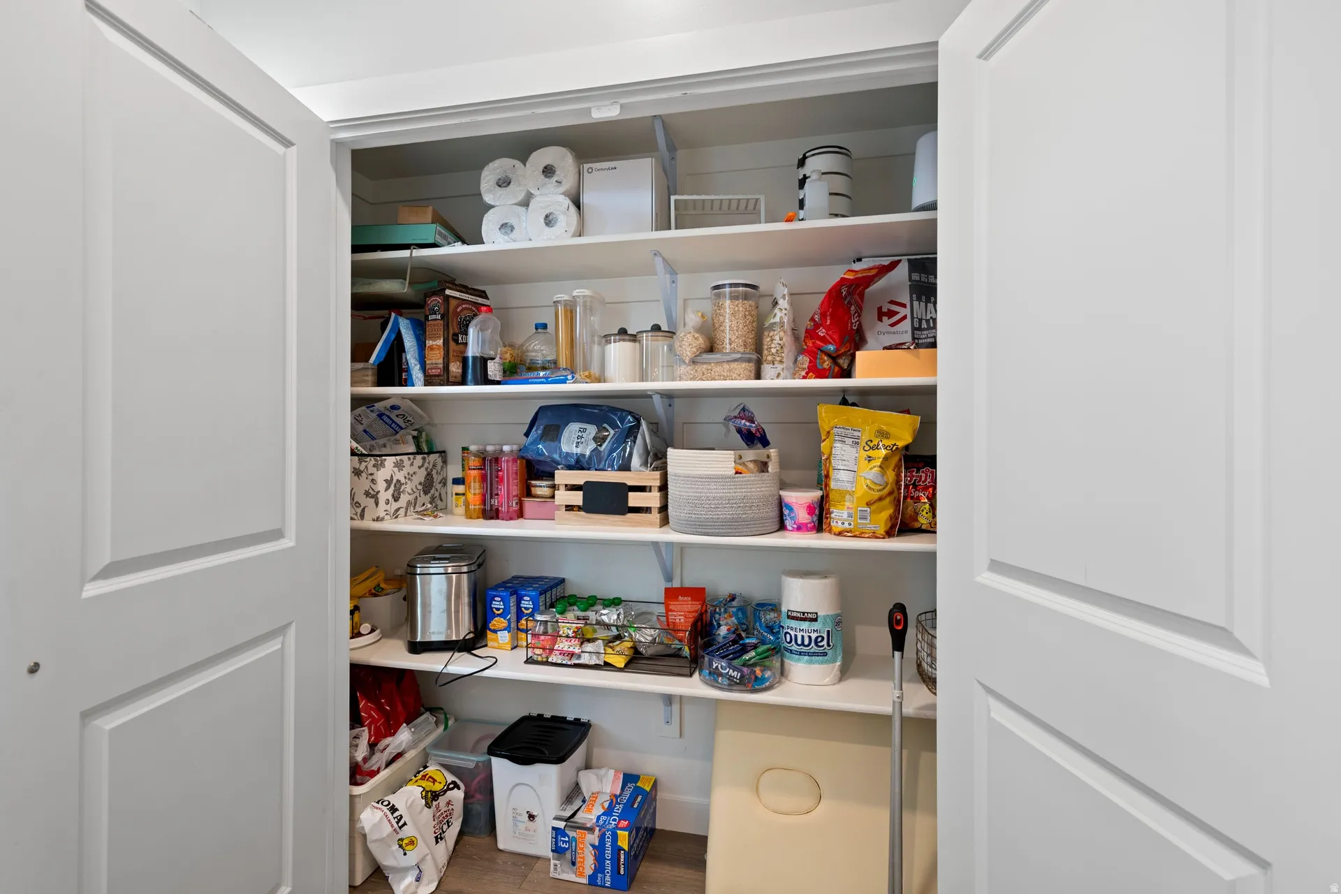Pantry featuring white shaker doors and multiple levels of shelving