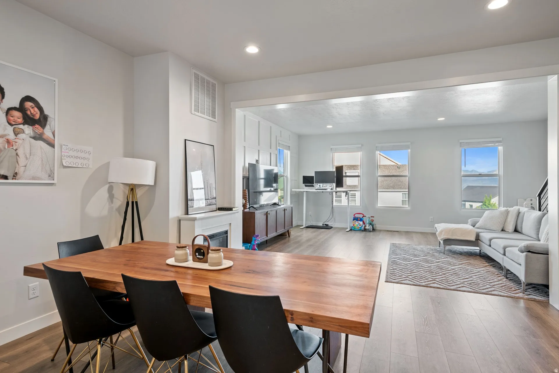 Open-concept living space featuring wood-finish flooring, recessed lighting, and a fireplace with a white mantel