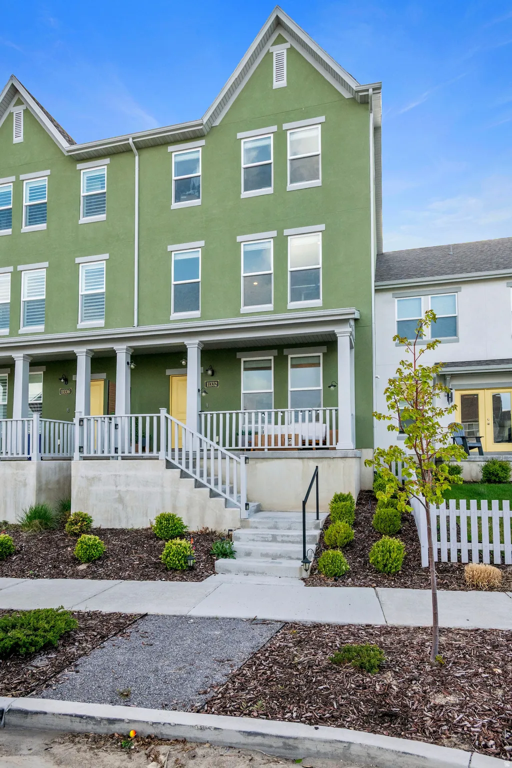 Contemporary townhome exterior featuring a pastel green facade and white trim