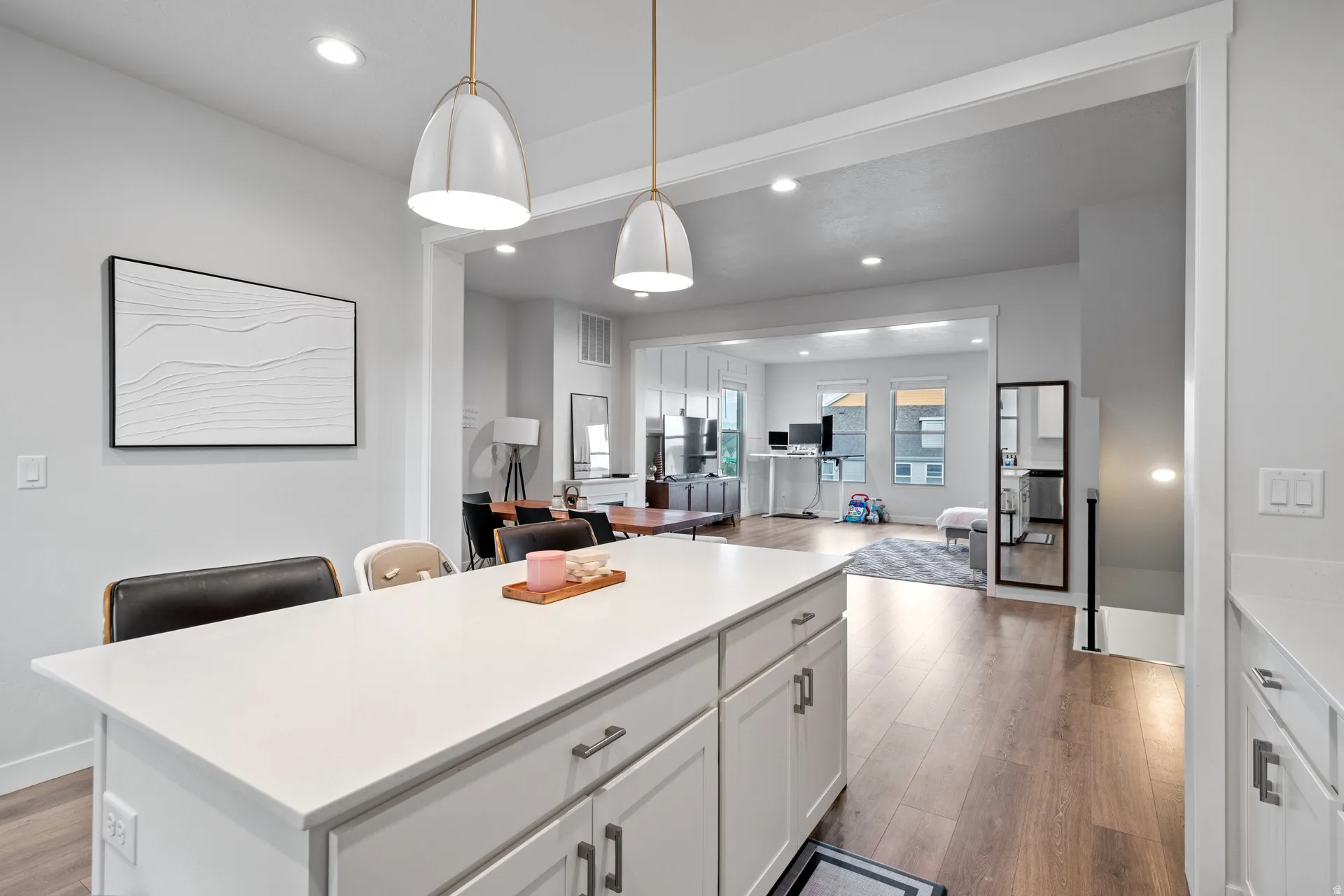 Kitchen island featuring a white countertop, two pendant lights, and white cabinetry
