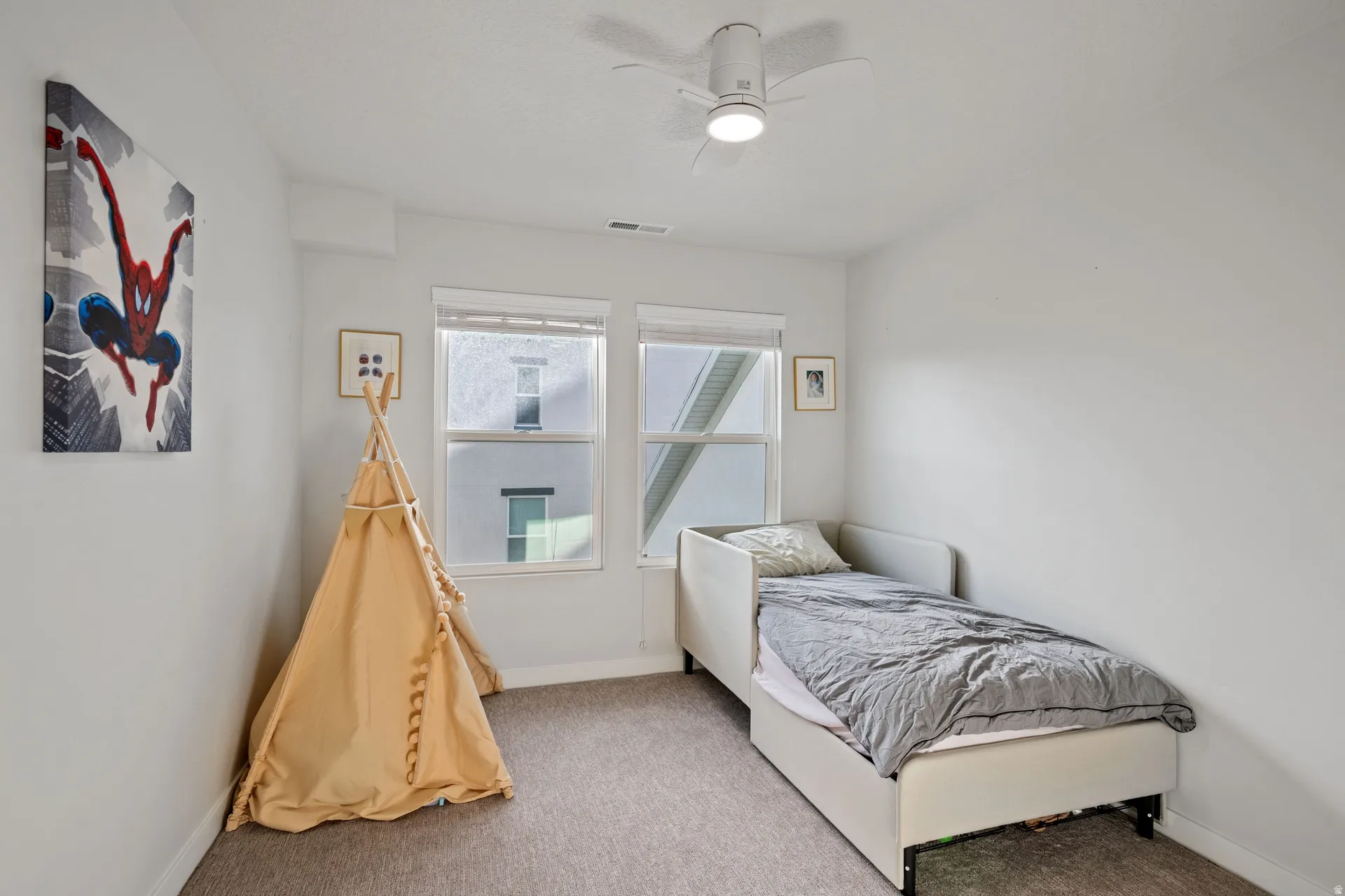 Light-filled room featuring two windows with blinds, a ceiling fan with integrated lighting, and neutral-toned carpeting