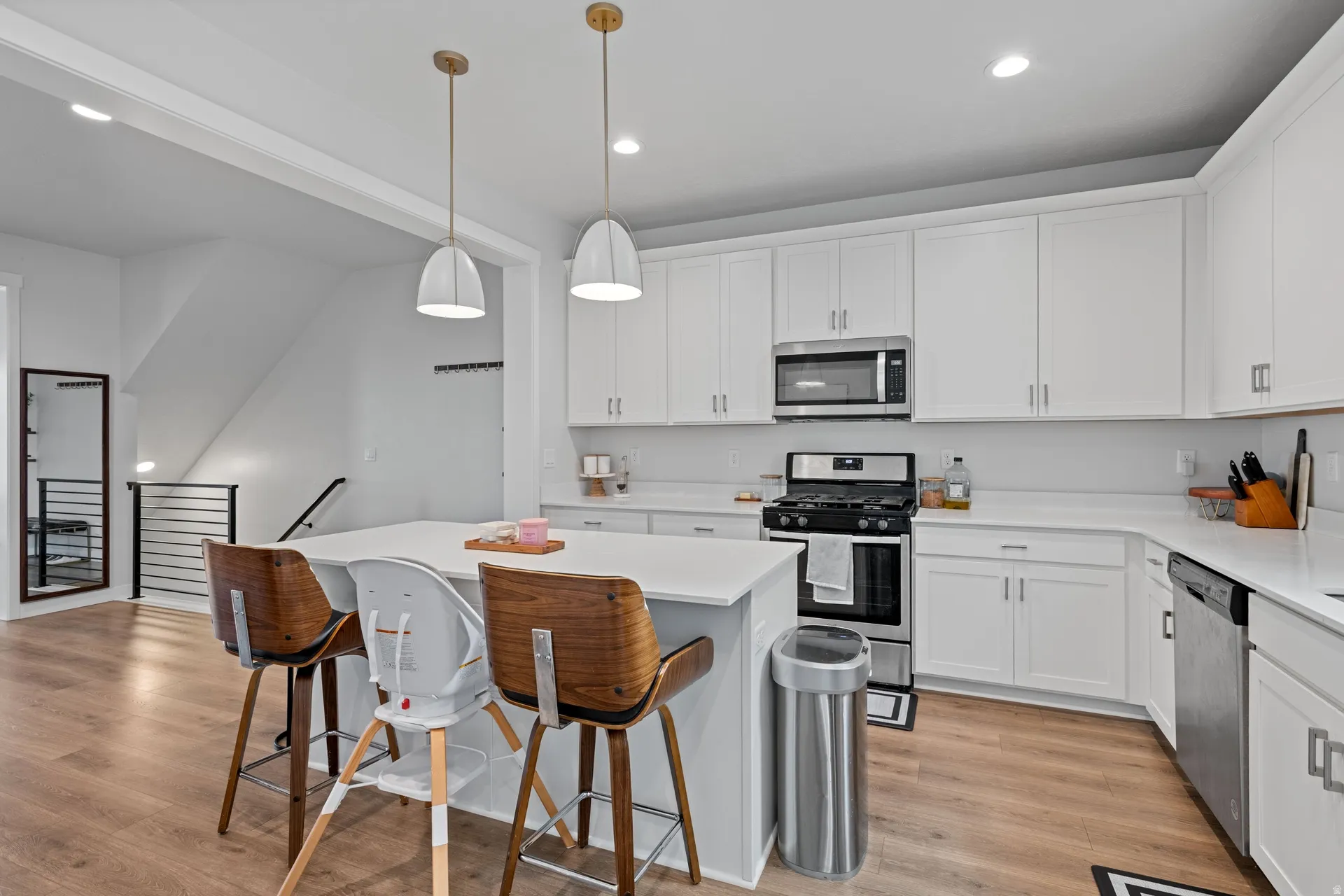 Contemporary kitchen featuring white cabinetry, light countertops, wood-finish flooring, and stainless steel appliances