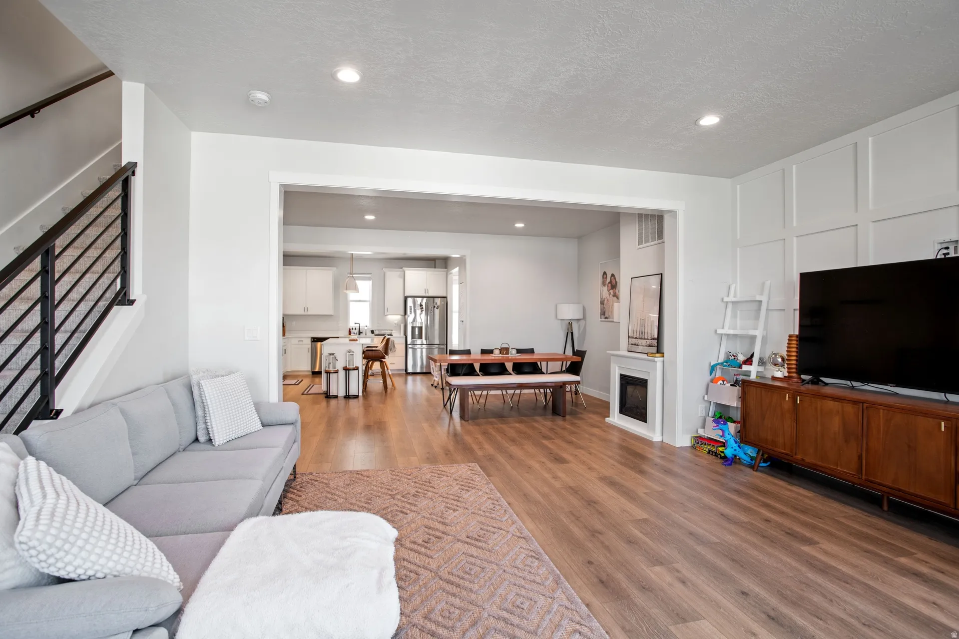 Open-concept living area featuring wood-finish flooring, recessed lighting, and a modern fireplace