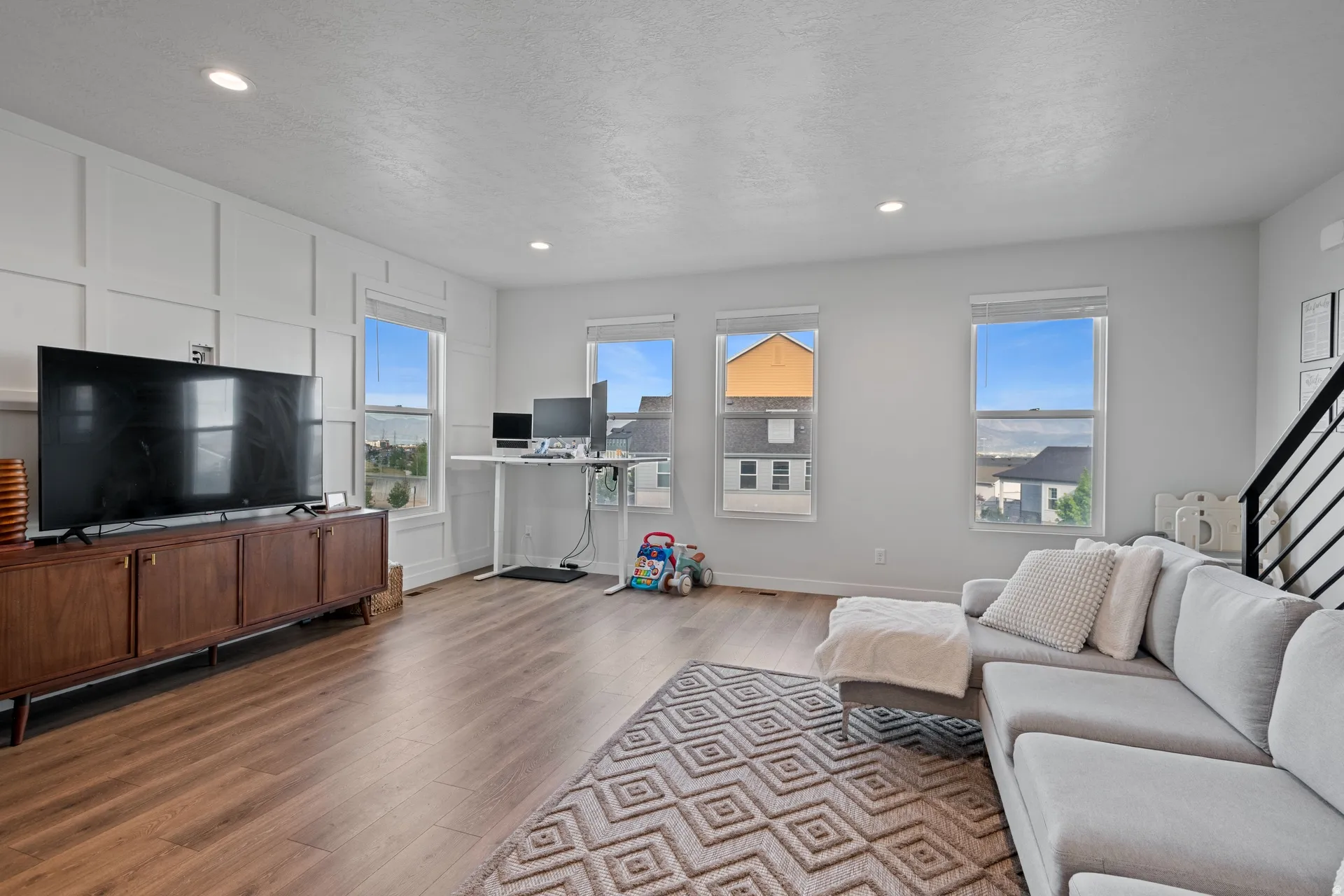 Spacious room featuring wood-finish flooring, recessed lighting, and bright windows