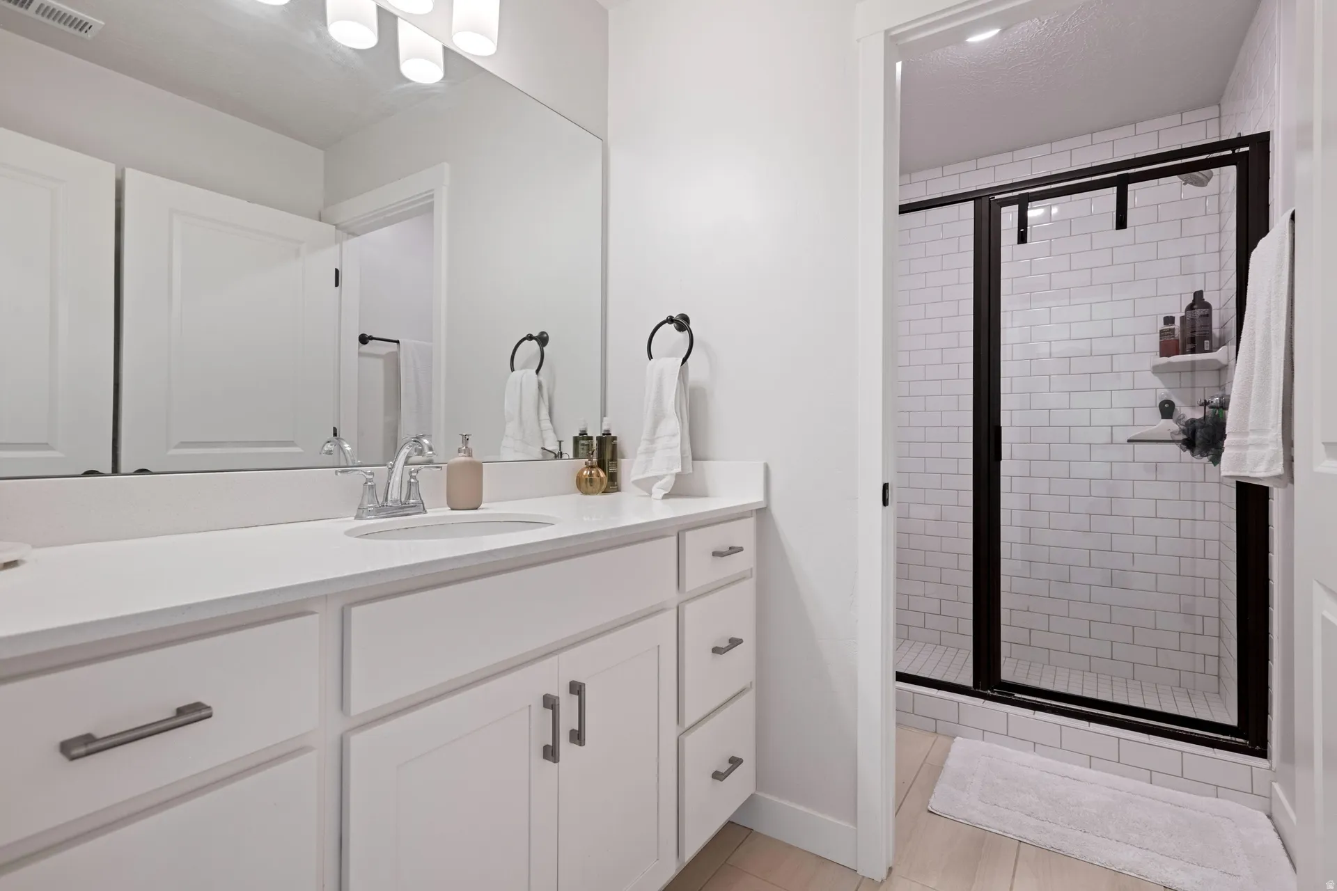 Bathroom vanity featuring a single basin, white countertop, and white cabinetry with brushed nickel hardware