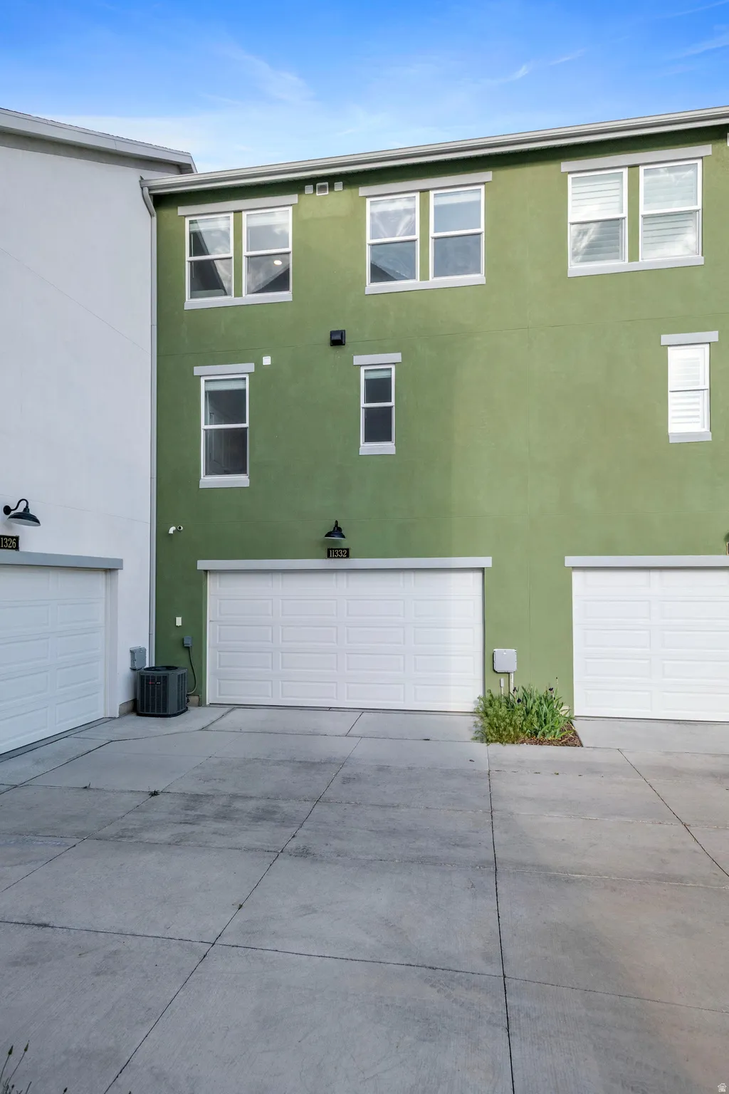 Multi-level stucco exterior with multiple windows and two single-car garage doors