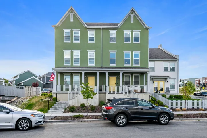 Contemporary townhome featuring a vibrant green stucco exterior and a contrasting white trim