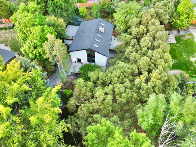 Modern multi-level residence with a dark shingle roof, multiple skylights, and a prominent chimney