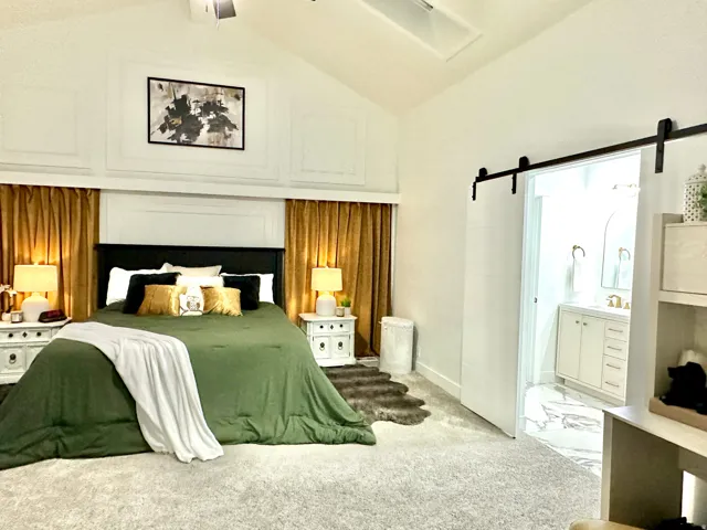Spacious bedroom with vaulted ceilings, featuring decorative wall molding and a ceiling fan