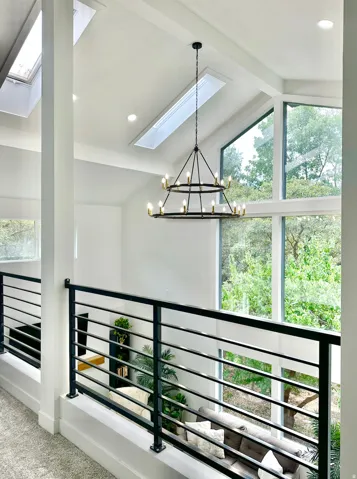 Vaulted ceiling featuring a tiered chandelier and multiple skylights