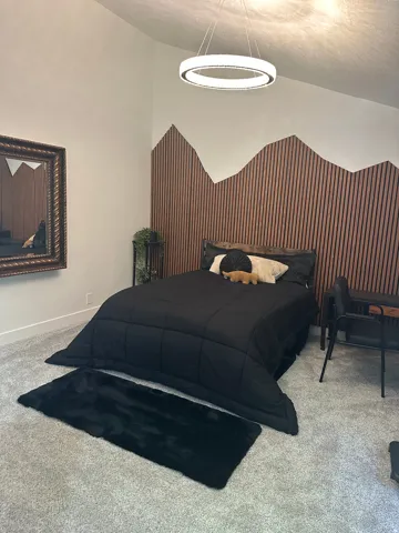 Vaulted ceiling with an attached contemporary chandelier, wall-mounted wood slat accent paneling, and wall-to-wall carpeting