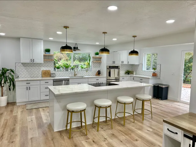 Modern kitchen featuring a white center island with a built-in cooktop, complemented by gold and black pendant lighting