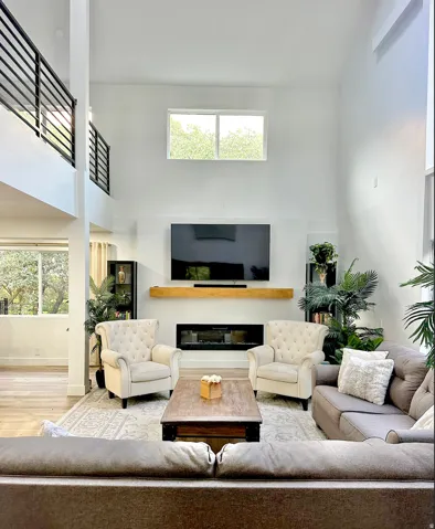 Living area featuring a two-story ceiling with an upper-level window and a contemporary fireplace with a wood mantle