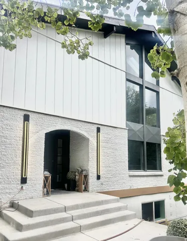 Modern home exterior featuring a prominent arched entry, white brick facade, and vertical siding