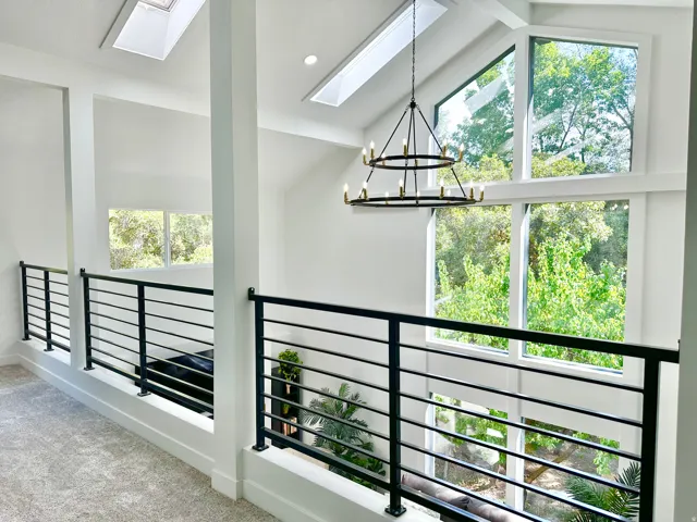 Two-story space featuring a contemporary chandelier, multiple skylights, and expansive windows