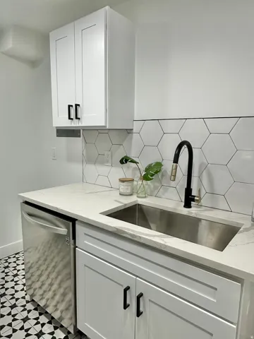 Sleek kitchen with white shaker-style cabinetry, a stainless steel undermount sink, and a black gooseneck faucet