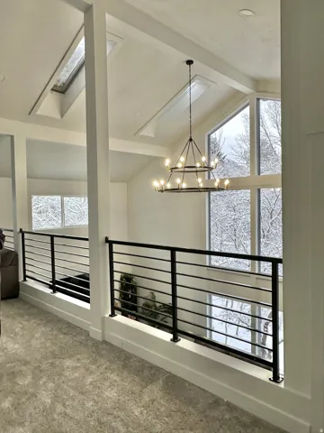 Spacious interior featuring a contemporary black metal railing, overhead chandelier, and multiple skylights