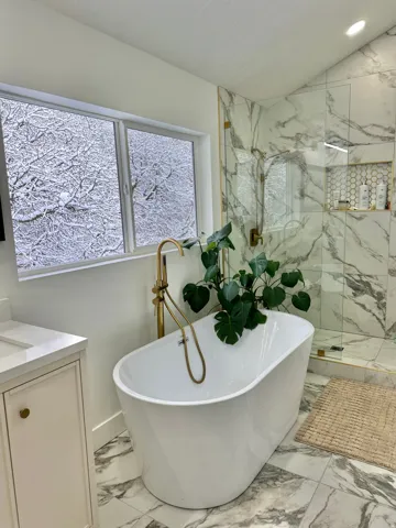 Freestanding soaking tub featuring a floor-mounted gold-finish faucet