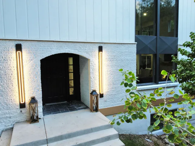 Arched entryway with a dark wood-finish door and vertical accent lighting