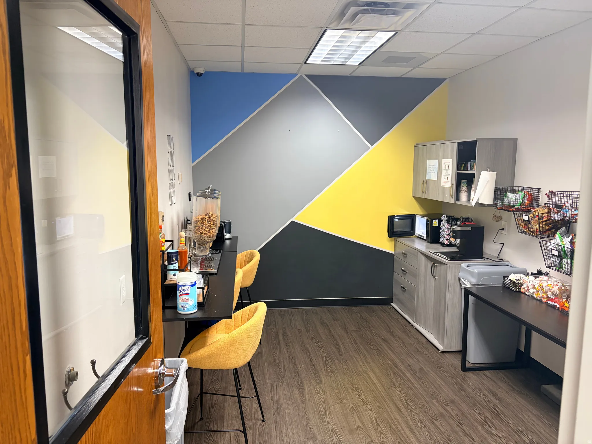 Functional breakroom with wood-finish flooring, geometric accent wall, and built-in cabinetry