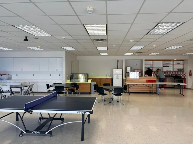 Spacious common area featuring durable flooring and grid ceiling with integrated fluorescent lighting