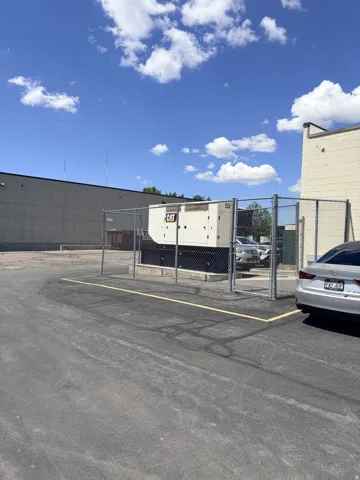Paved outdoor lot featuring a fenced industrial generator