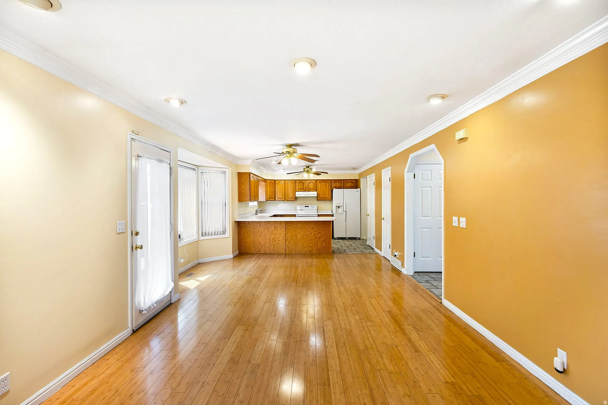 Open-concept living area featuring wood-finish flooring, recessed lighting, and crown molding