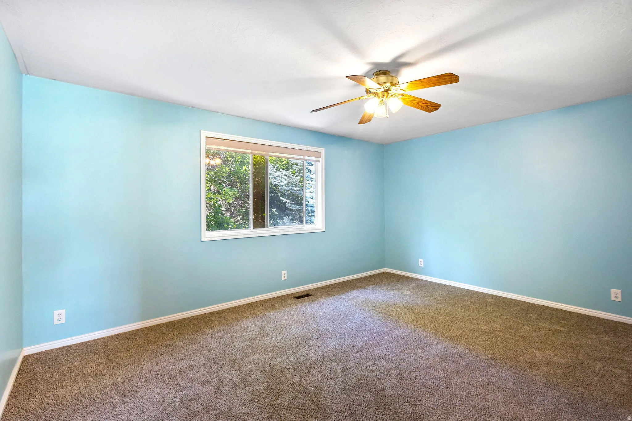 Bedroom #4, Spacious room featuring light blue walls, a large window with natural light, a ceiling fan with light fixture, and neutral-toned carpeting