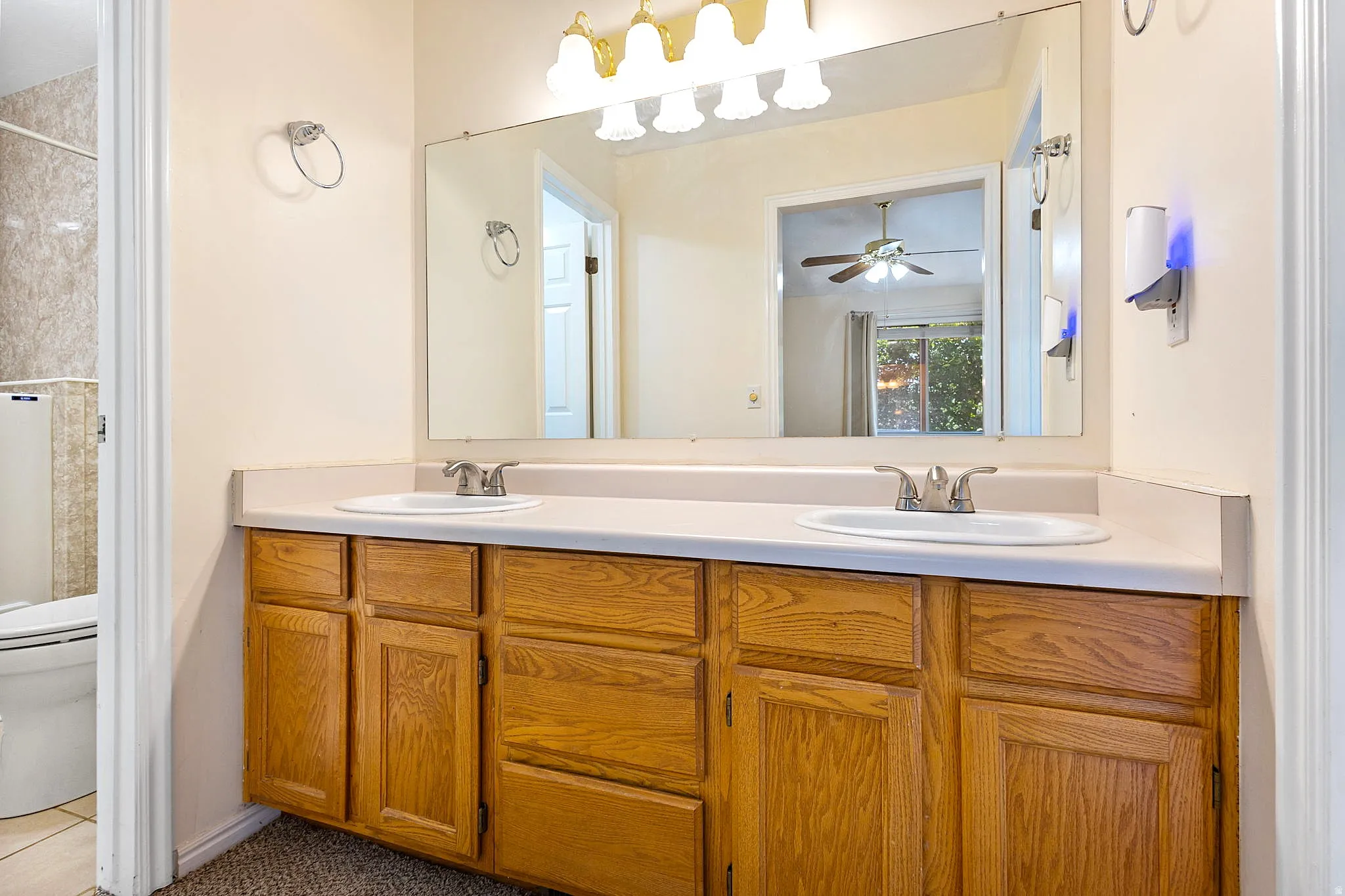 Primary bathroom, double vanity with two integrated sinks, light-toned countertop, and wood-finish cabinetry