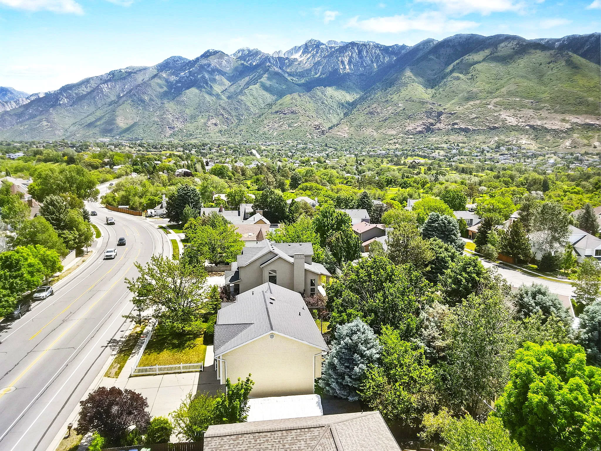 Side shot of home with expansive mountain backdrop framing a residential area with mature trees