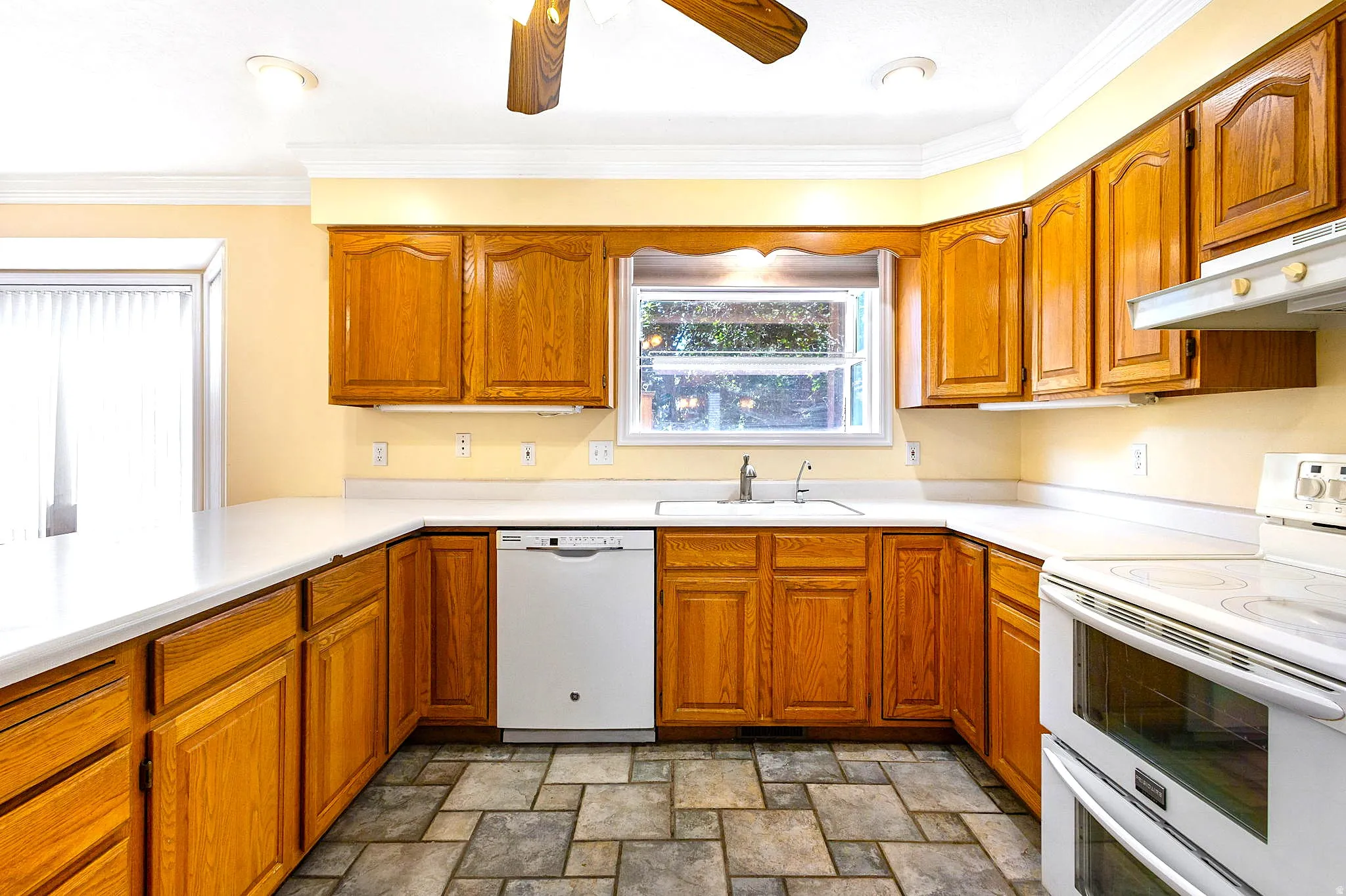 Kitchen featuring wood cabinetry, white countertops, a built-in dishwasher, and a double-oven range