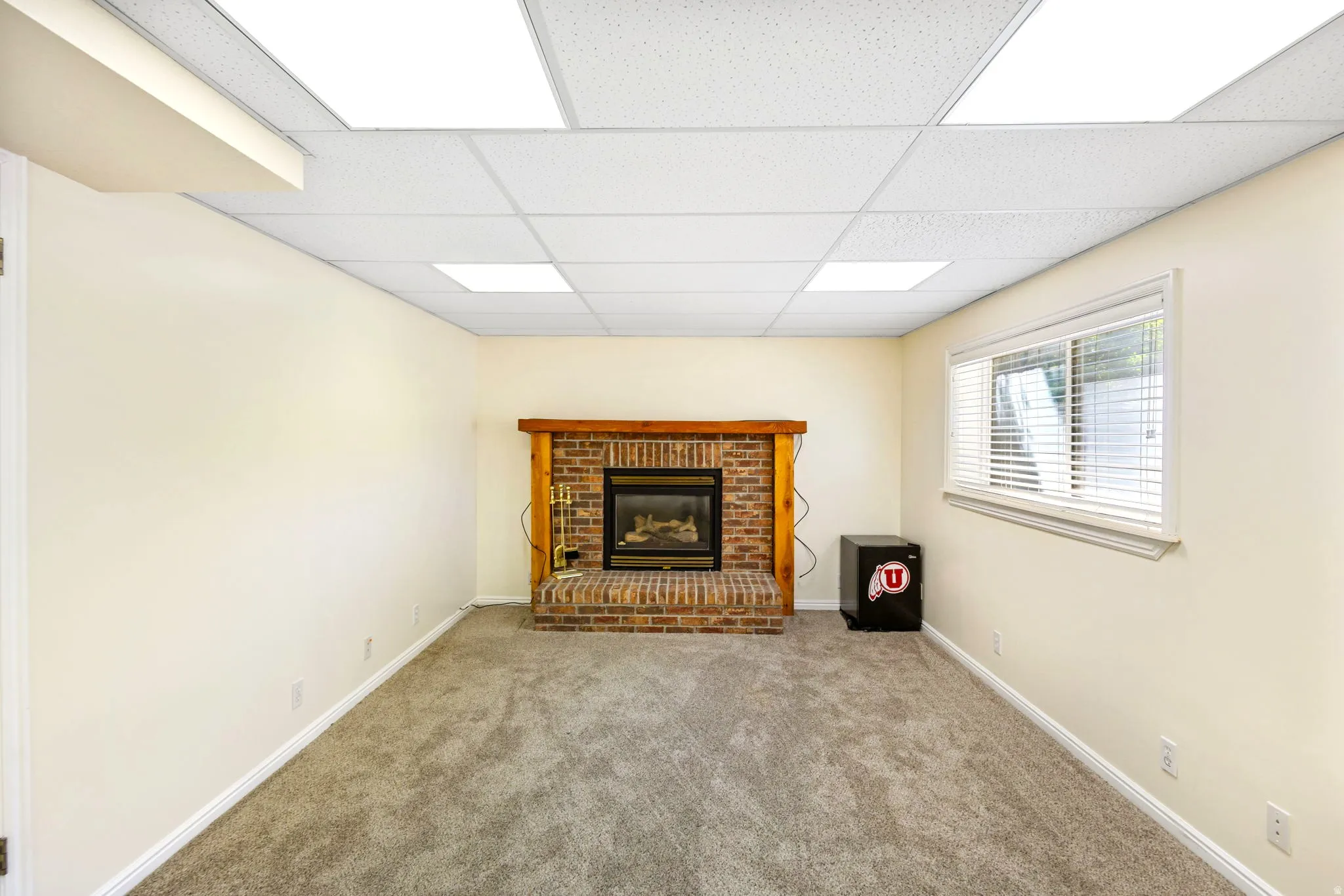 Carpeted room featuring a brick fireplace with a wood-finish mantel and a built-in firebox