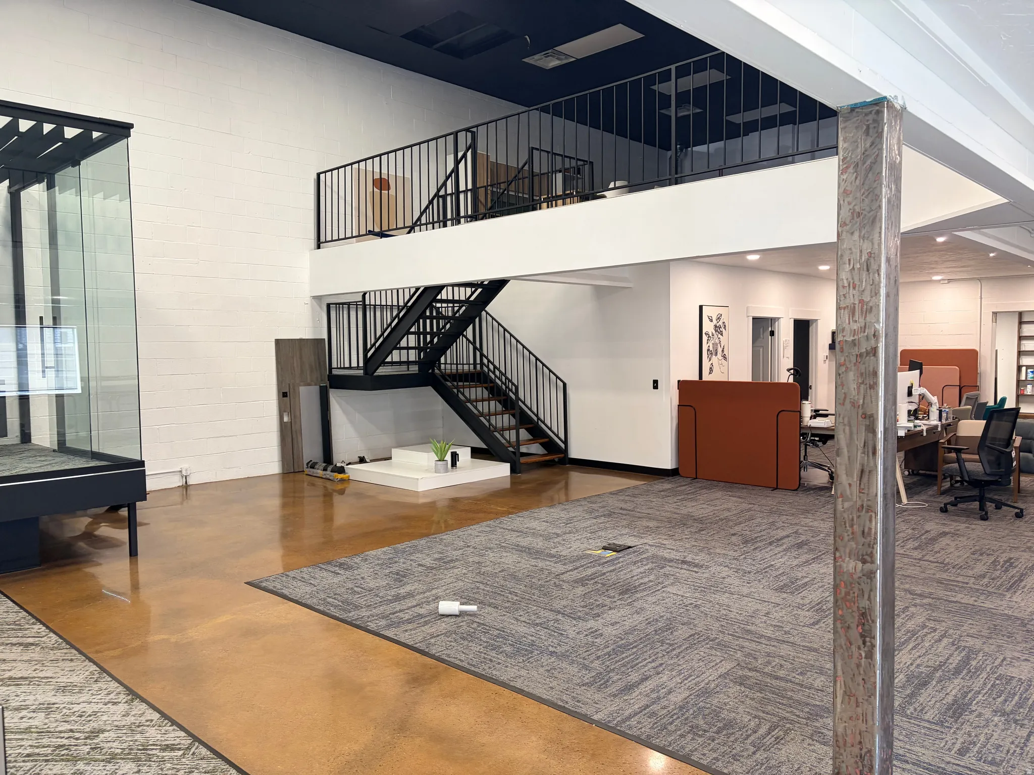 Multi-level interior featuring a black metal staircase and railing, a finished second-story loft, polished concrete flooring, and carpeting in various sections