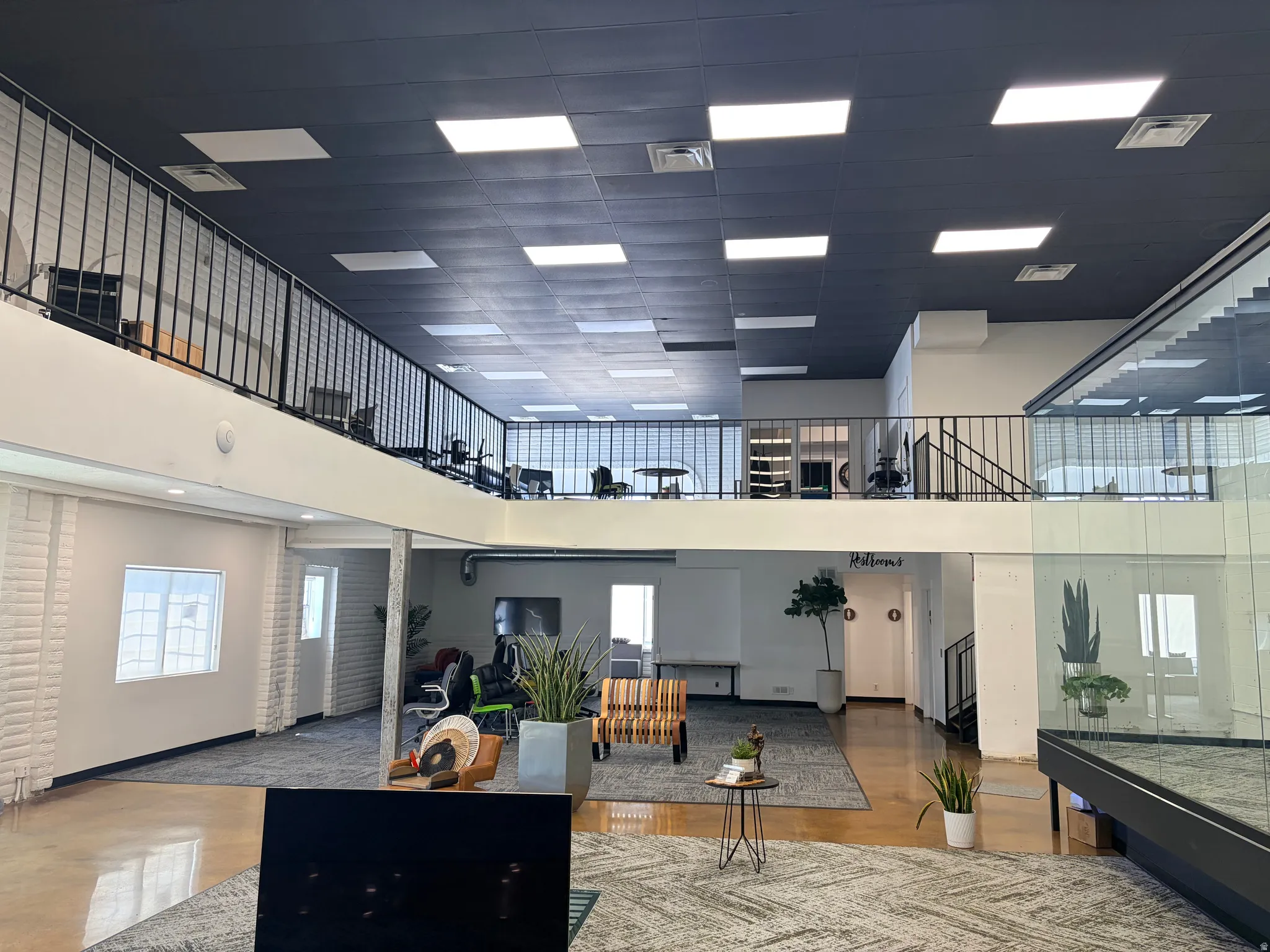 Two-story commercial interior with a ground-level open area and an upper-level mezzanine