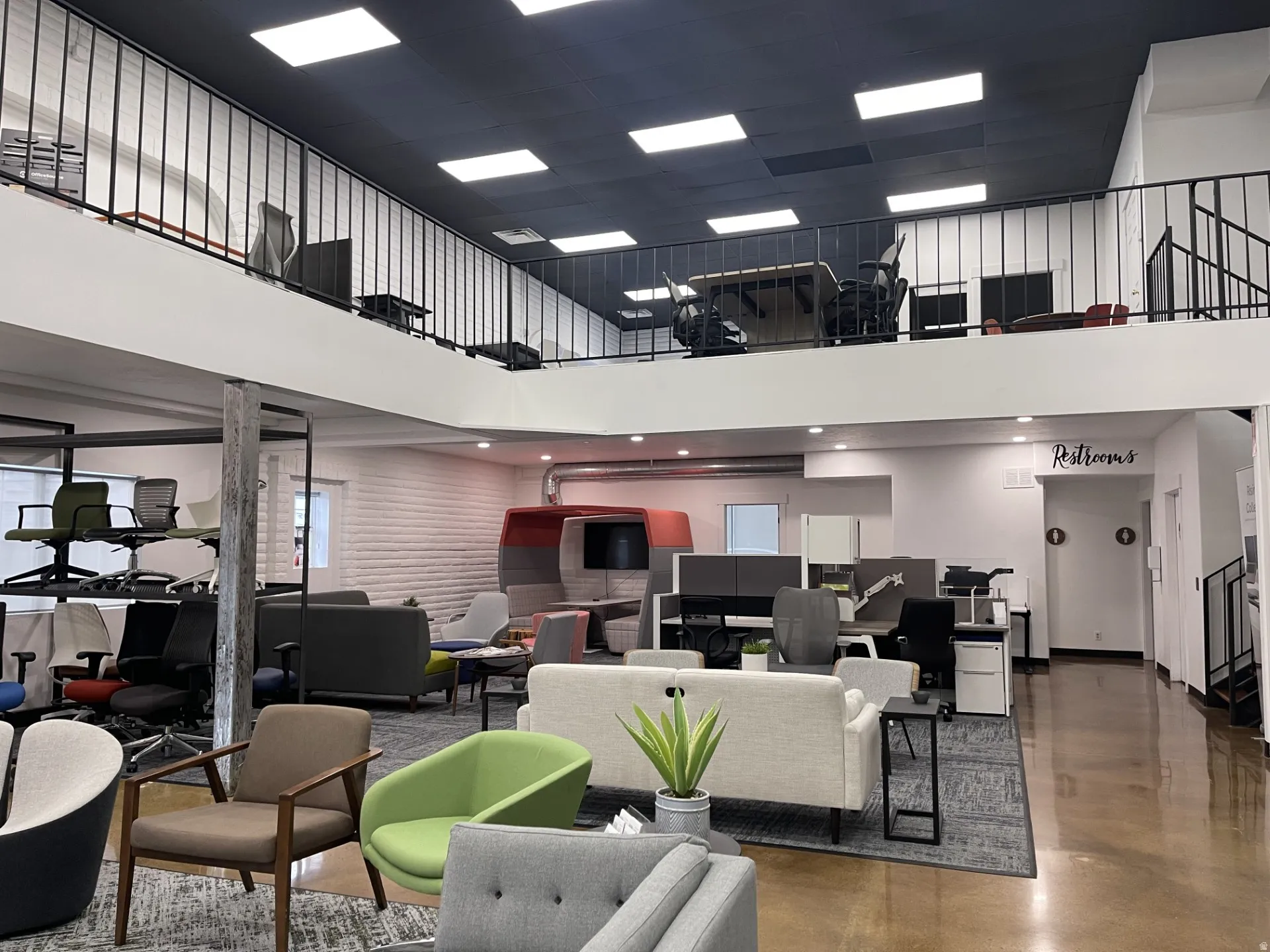 Open-concept commercial space featuring a prominent mezzanine level with black metal railings