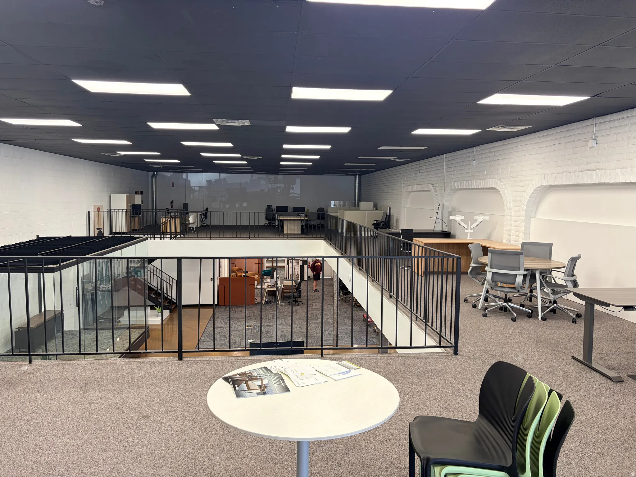 Mezzanine level featuring a black ceiling, recessed lighting, and a white brick-textured accent wall with arched architectural details