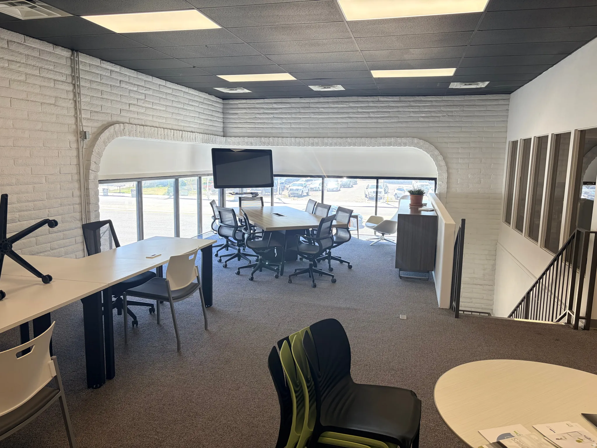 Open-concept workspace featuring white painted brick walls and broad windows with roller shades
