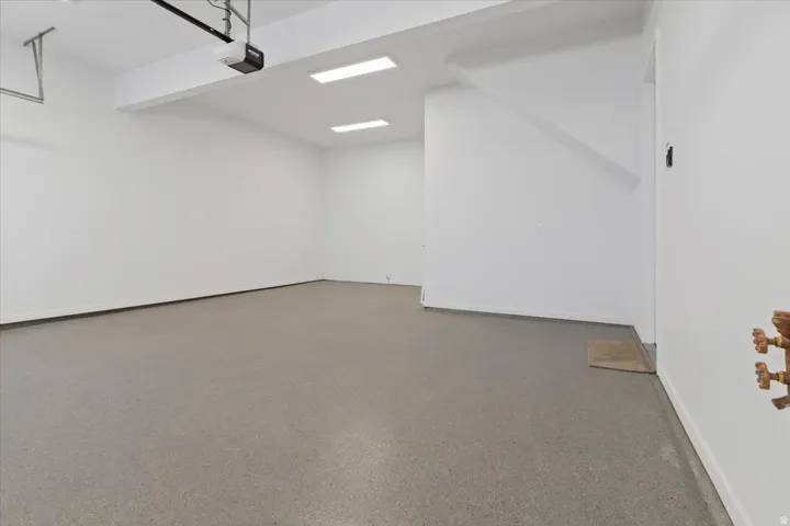 Spacious garage featuring a durable epoxy-coated floor, bright overhead lighting, and an automatic garage door opener