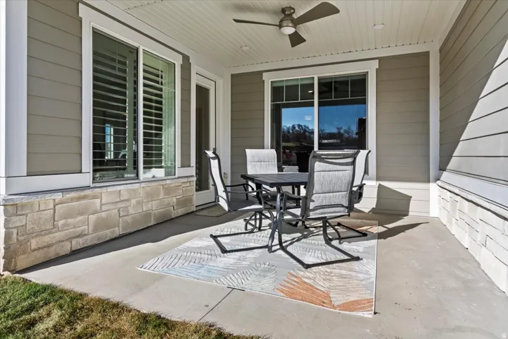 Covered patio featuring a ceiling fan, stone veneer foundation, and siding exterior