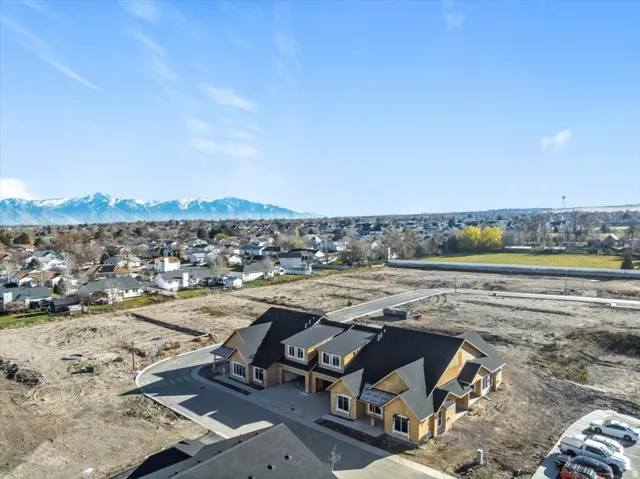 Newly constructed townhomes featuring dark shingle roofing, light-toned siding, and visible window framing