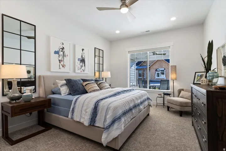 Spacious bedroom with vaulted ceilings, recessed lighting, and a window overlooking an outdoor patio space