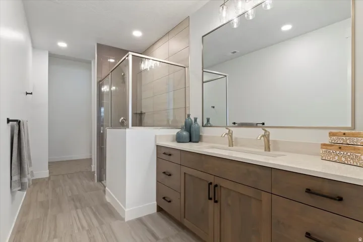 Double vanity with a light-toned countertop, wood-finish cabinetry, and brushed nickel fixtures