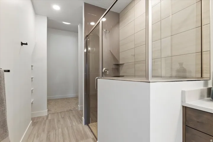 Walk-in shower with clear glass enclosure and light-toned tile surround