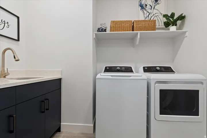 Laundry area featuring a built-in sink with a gold-finish faucet, dark cabinetry, and light-toned countertop