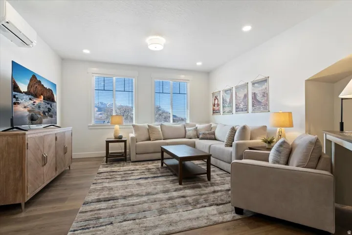 Spacious living area featuring light wood-finish flooring, recessed lighting, and white walls
