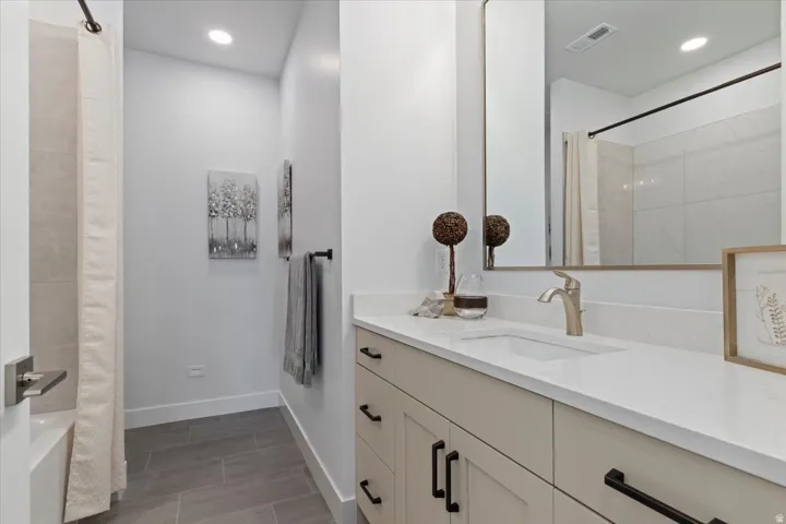 Bathroom vanity featuring a light-colored countertop with an integrated sink, brushed nickel faucet, and a large wall-mounted mirror